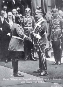 Die Generale Hans Georg von Plessen (Bildmitte) und Moriz von Lyncker (rechts) beobachten Kaiser Wilhelm II. und Otto von Emmich, den Kommandeur des X. Armee-Korps. Dritter von links ist der Stadtdirektor von Hannover, Heinrich Tramm. Anläßlich der Einweihung des Neuen Rathauses in Hannover wartet er geduldig, während der Kaiser zuerst den General Emmich begrüßt.