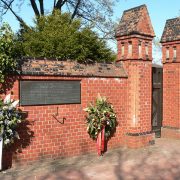 Mahnmal mit Inschrift und Kränzen am alten Eingangstor neben dem ehemaligen Direktorenhaus