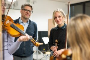 Thomas Weinert, Vonovia Regionalleiter Hannover, besucht Geigenlehrerin Rebecca Czech und ihre Schülerinnen und Schüler beim Geigenunterricht